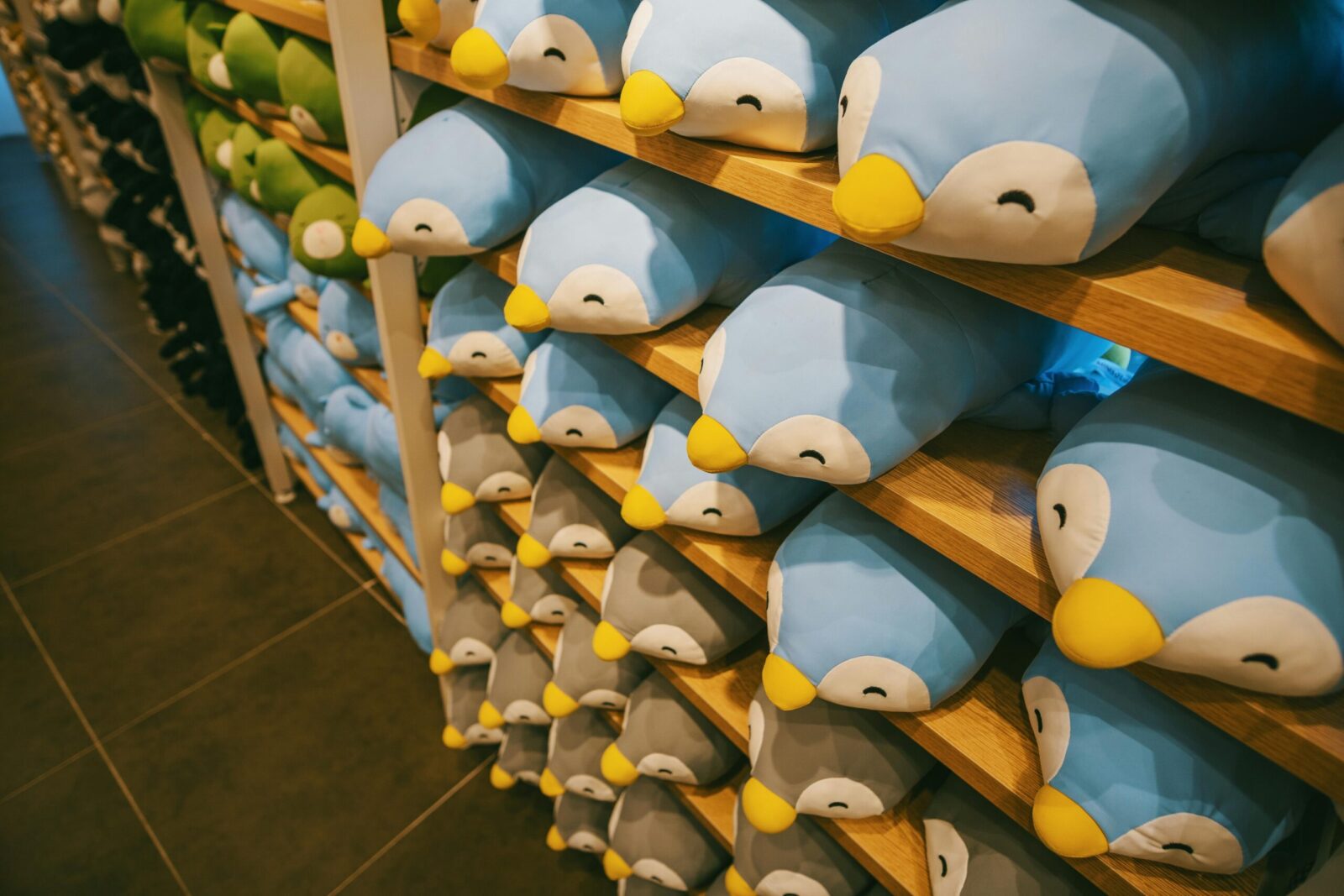 Rows of adorable penguin plush toys on wooden shelves creating a cozy indoor display.